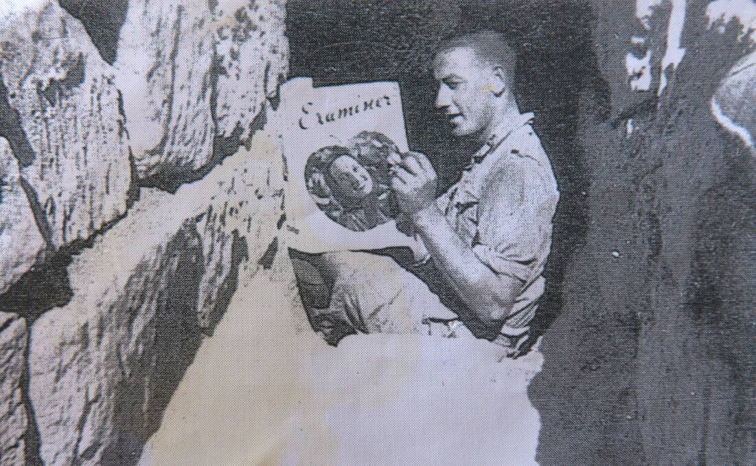 WAR STORIES: George Henderson pictured in the trenches in 1941 reading The Examiner. Mr Henderson is the last surviving Tasmanian-born Rat of Tobruk and will celebrate his 100th birthday on March 16. Picture: Supplied