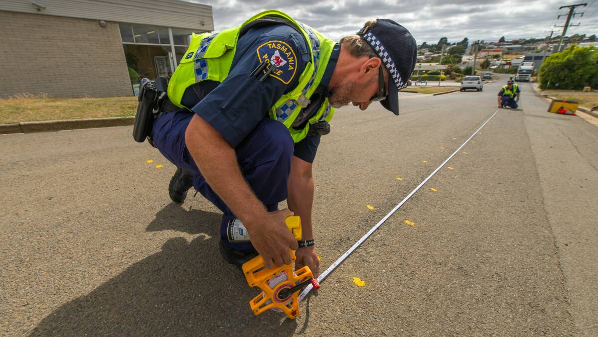 ANALYSIS: First-Class Constable Housego measures markings on the road with Senior Constable Rybka, one step in a long process to determine the cause of a crash.