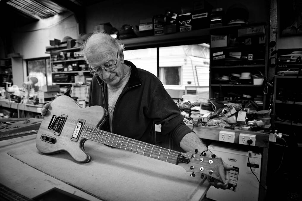 STRUNG OUT: Mr Phillips examines a StringWorx Custom Guitars guitar at his workspace in his shed. 