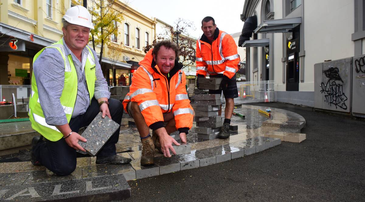 PROGRESS: Nigel Baker, Owen Milbourne and Ashley Quigley start laying pavers in the Quadrant Mall. Photo: Paul Scambler