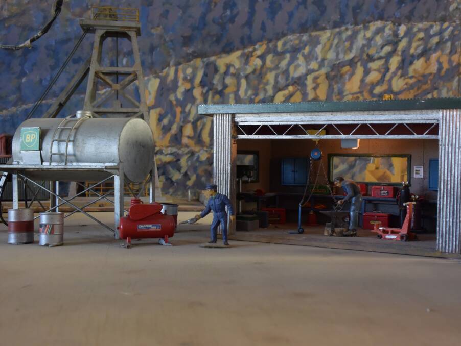 Miniature workmen in a shed near an escalator transporting crushed stone at the site.