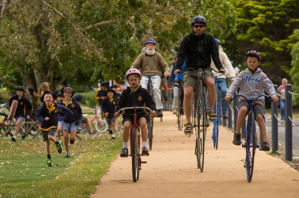 Marguerite McClintock, Jeff McClintock and Sam Mahboub lead the penny farthing parade into the Evandale Primary School grounds. Picture: Phillip Biggs