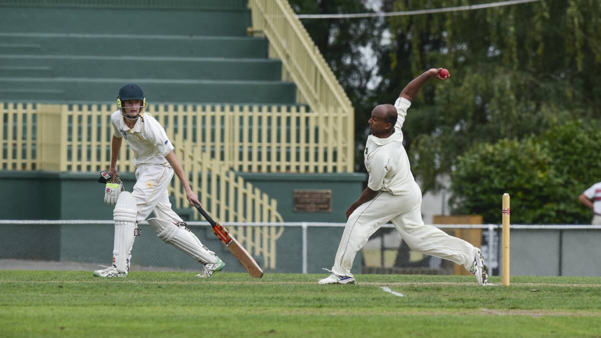 Jacob Kooran bends his back as he sends down a delivery with South Launceston's James Beattie watching on.
