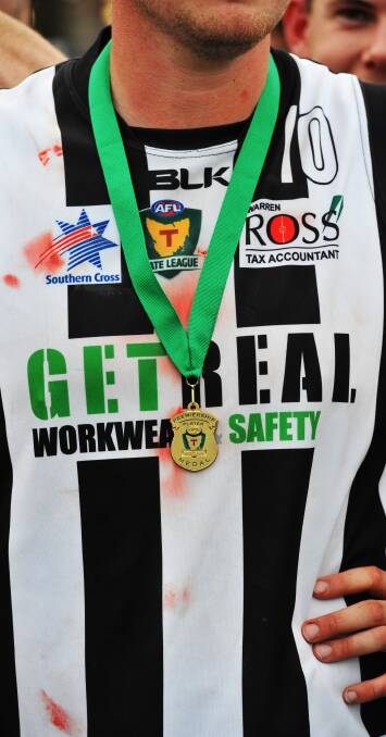 PHYSICAL: A premiership medal hangs on top of the blood-stained jumper of Glenorchy's Tyler Bowden after the match.
