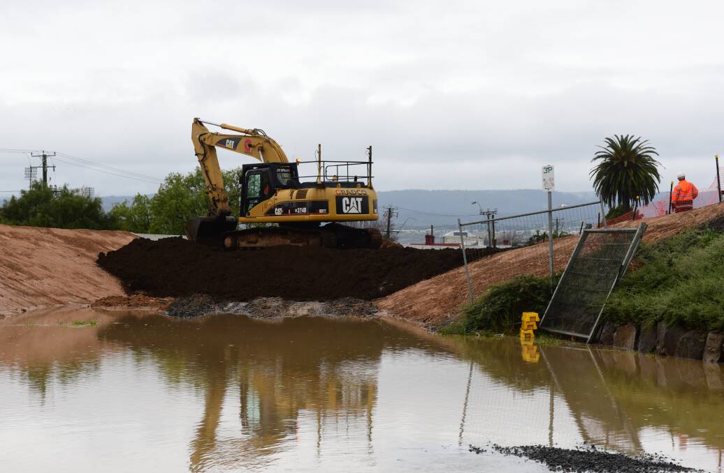 An excavator backfills the levee behind the North Esk Rowing Club.