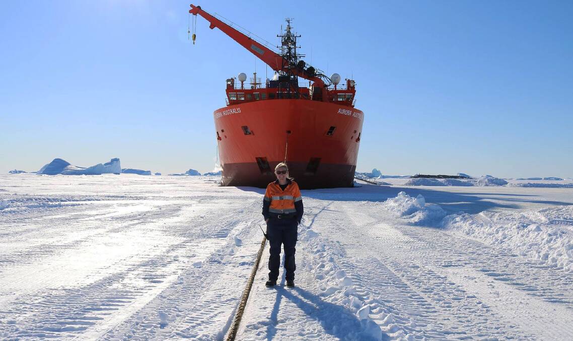 Station Supply Officer, Jen Proudfoot in front of Australia’s Antarctic icebreaker, Aurora Australis at Davis Research Station. Pictures: Vasili Georgiou, Australian Antarctic Division