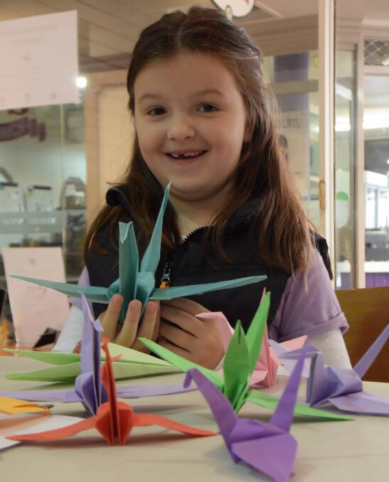 PEACE: Six year old Sarah Ringsgwandl, of Launceston, helps to make 1000 cranes for the Tamar Valley Peace Festival, which are on vibrant display in the Old Brisbane Arcade. Picture: Piia Wirsu
