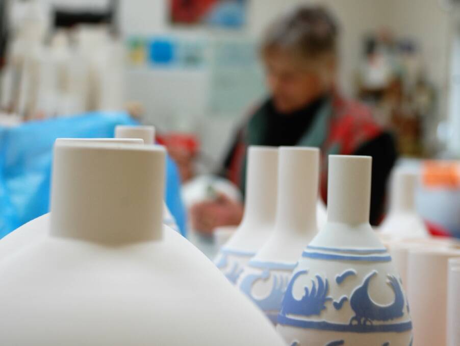 Alting works on a design, surrounded by works ready for painting, sanding and glazing. Creating fine porcelain involves double firing and multiple sandings. 