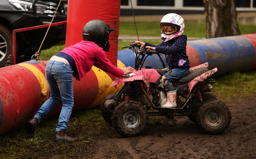 STUCK IN THE MUD: Isabelle Ackerly, 9, helps her sister, Imogen, 5, after a crash while riding the junior quad bikes at the Royal Launceston Show. The pair were most excited to see the ponies. Picture: Scott Gelston.