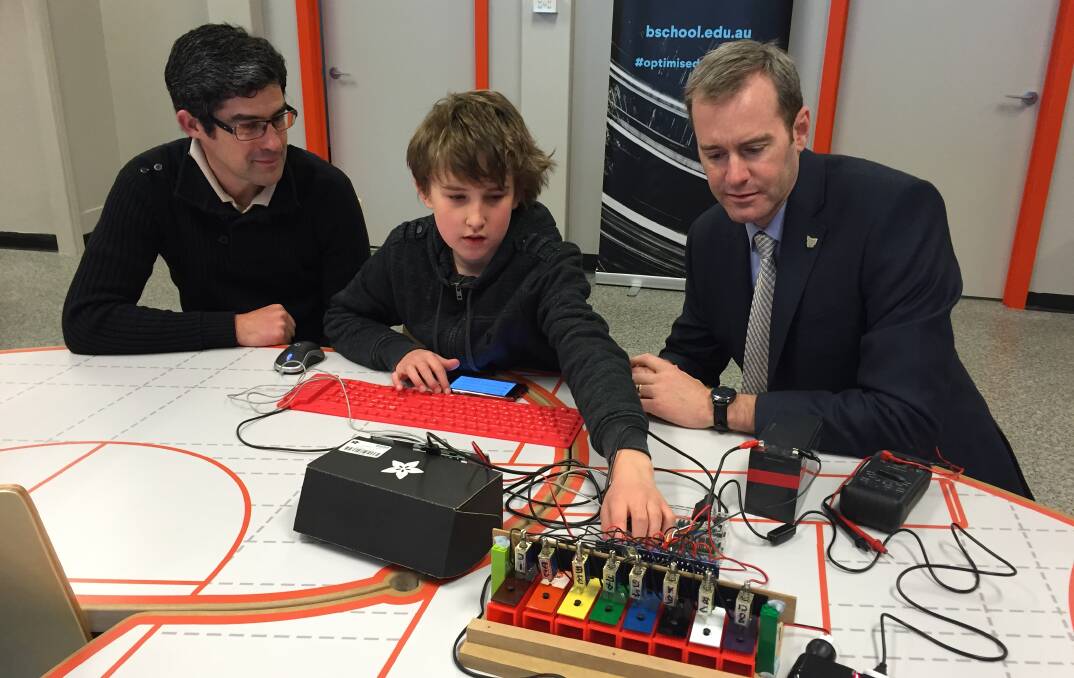 YOUNG INNOVATOR: Eleven-year-old William Cook discusses his music box project with Information Technology and Innovation Minister Michael Ferguson, while his father David Cook watches on. Picture: Holly Monery