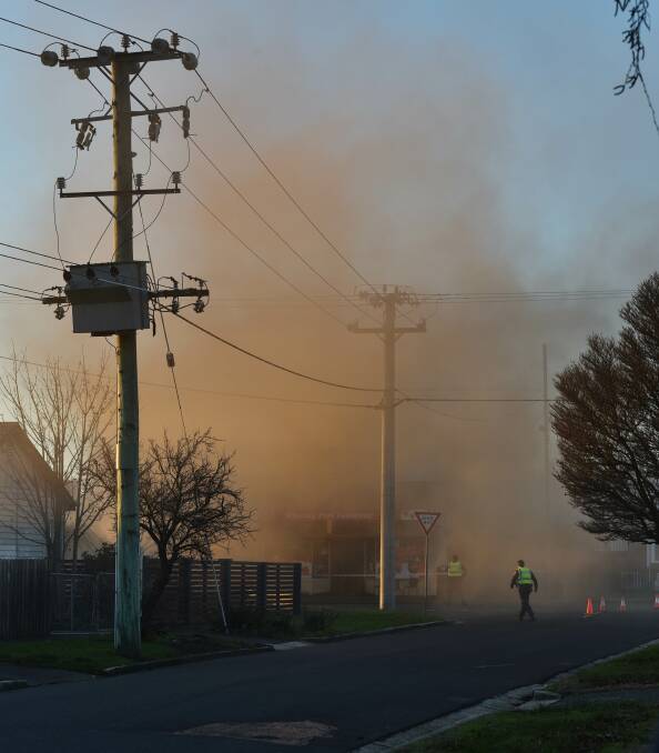 SMOKE GRENADE: Smoke billows from the Winning Post Takeaway and neighbouring property during the stand-off. Picture: Scott Gelston.