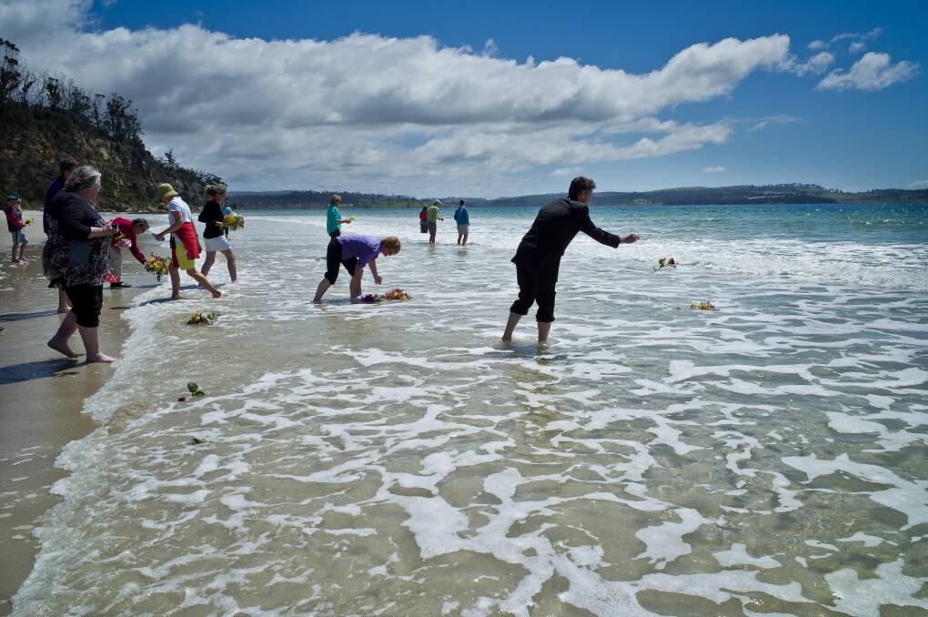 REMEMBERING: East Coast residents cast flowers into the water at Spring Beach at the 2015 Spring Bay Suicide Prevention Network memorial day. Pictures: Supplied