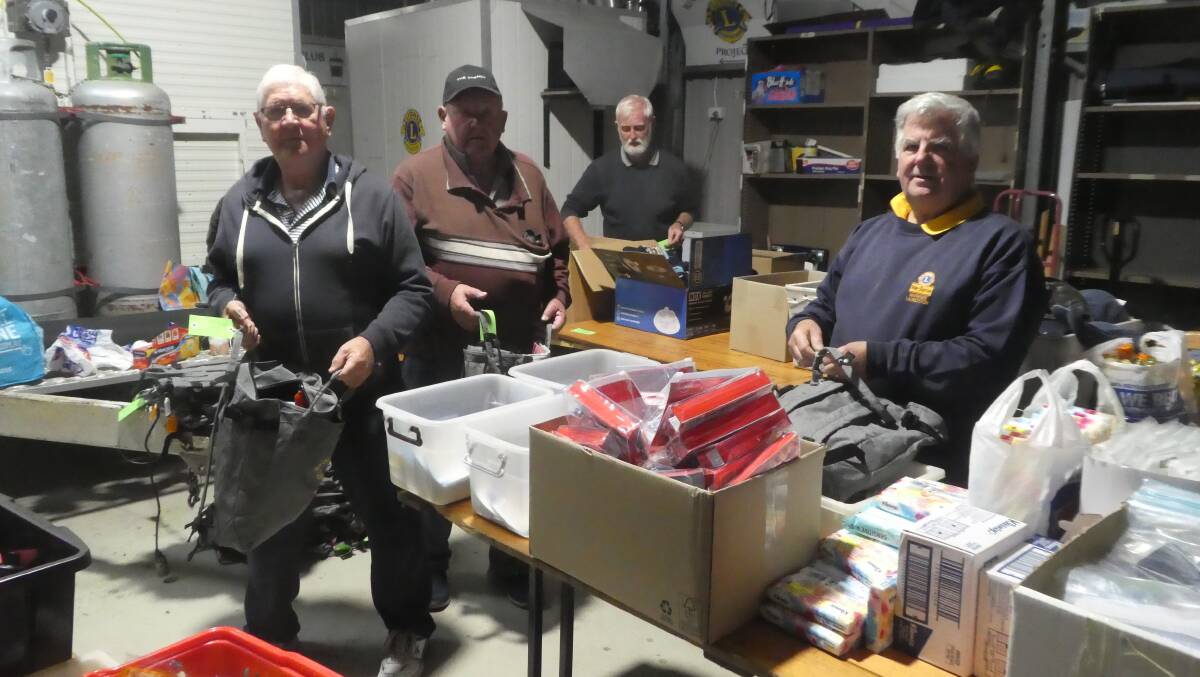 Rod Peck and Brian Dunham of the Riverside Lions Club with Louise Cowan of Shekinah House, and some of the 50 backpacks for homeless people in Launceston. Picture by Paul Scambler