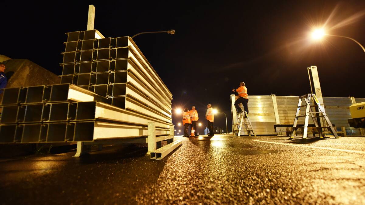 Floodgates being installed on the Charles Street Bridge on Tuesday night. Picture: Scott Gelston. 