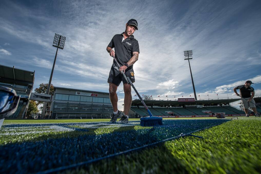 BLUE: Wazz Veale of Melbourne based sign writers business, Ausign, gets to work painting the UTAS Stadium turf. Picture: Scott Gelston 