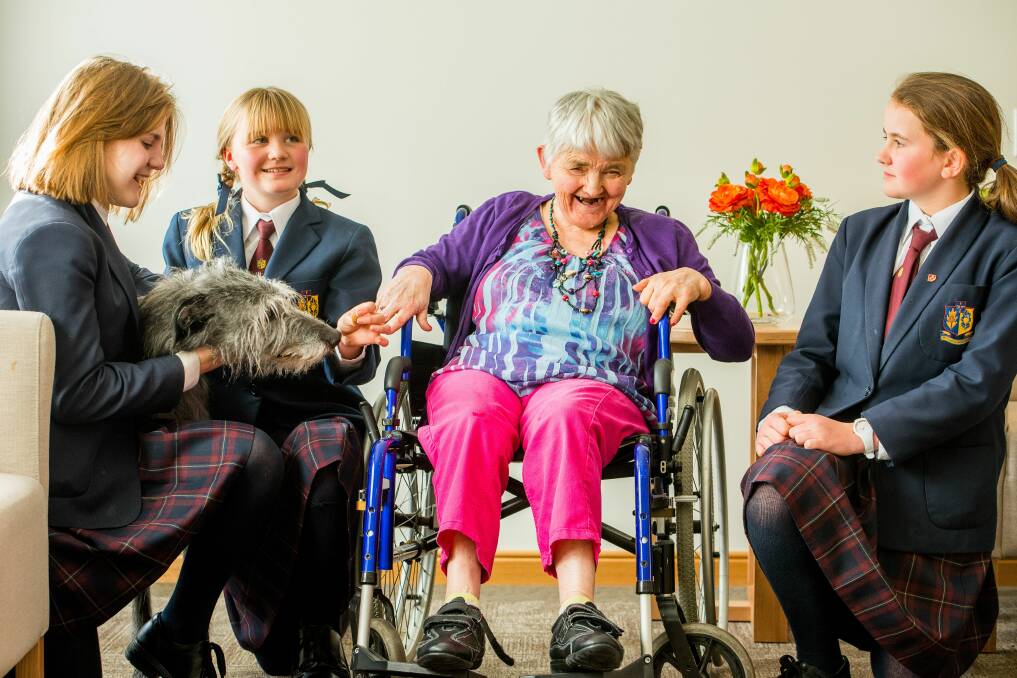 Scotch Oakburn College students Sasha Yuvchenko, Chloe Leersen and Ella Robinson visit Marlene Loosmore with Beau, the therapy dog, at Fred French aged care facility. Picture: Scott Gelston