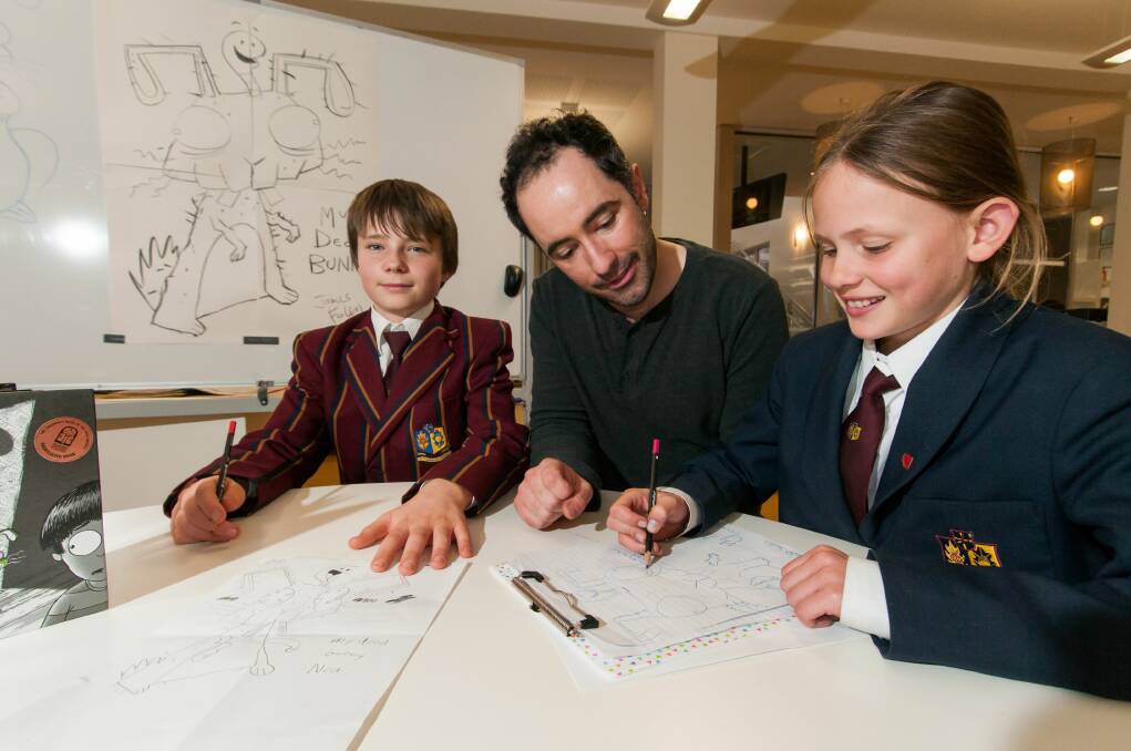 QUIRKY DRAWING: Illustrator and children's author James Foley draws a dead rabbit with students Ned Neville-Clark, right, and Leelah Jacobs. Picture: Phillip Biggs