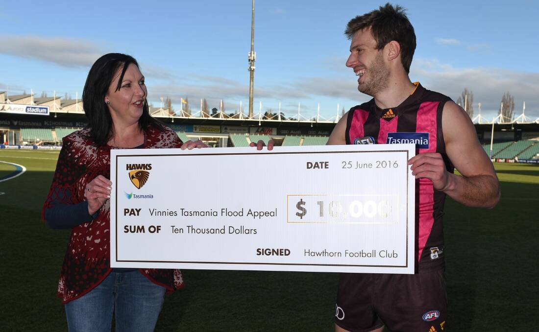 GENEROSITY: St Vincent de Paul Tasmania CEO Merleen Cronin happily receives a $10,000 cheque from Hawks star Grant Birchall on behalf of the Hawthorn Football Club to assist in Vinnies' ongoing flood appeal. Picture: Scott Gelston