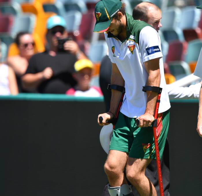 HURTING: Rising Tasmanian swing bowler Gabe Bell hobbles away on crutches during the Sheffield Shield clash on Sunday against Queensland at the Gabba. Picture: AAP.