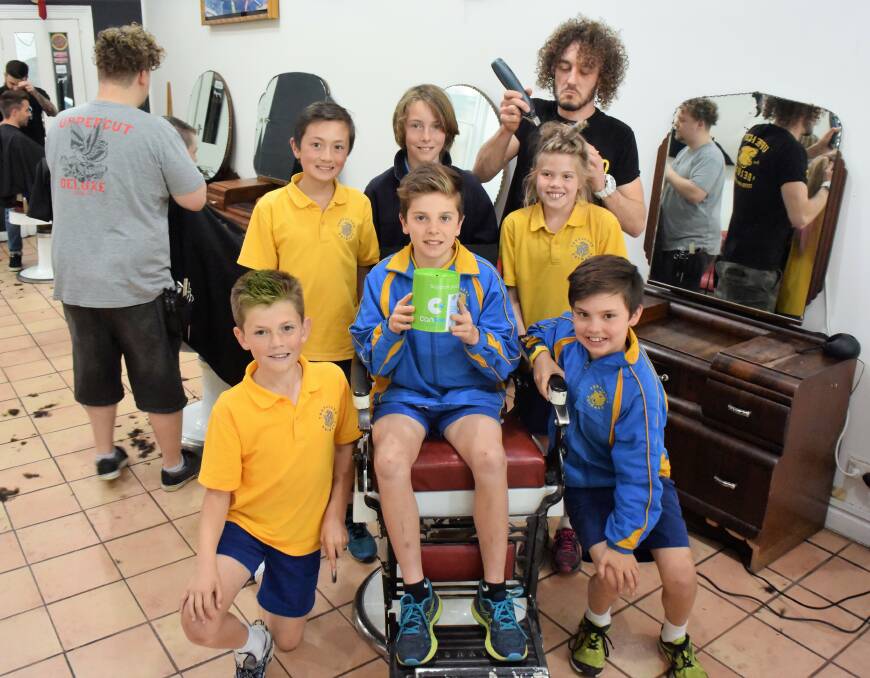 Just a trim: Trevallyn Primary grade 6 pupils Cade Sather, Oskar Small, Taj Barbour, Sam Hugo (chair), Alice Egan and Jordan Shipp with Hamish Mackean at Barber on George. Picture: Lucy Stone