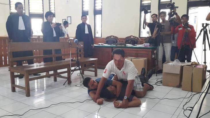 Pullman Hotel security guard Suryana (in blue shirt) plays Sara Connor in a reenactment at Denpasar District Court on Tuesday. Photo: Amilia Rosa.