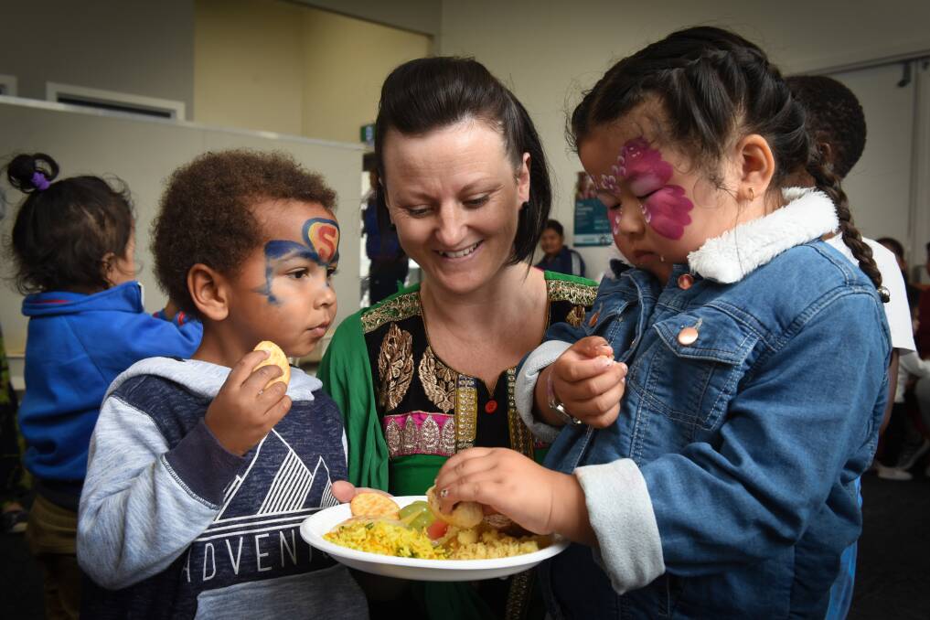 YUM: Lagu Thomas, 3, with playgroup coordinator Bec Blair, and Sharon Tamang, 4, share a plate of food at Monday's celebration. Picture: Paul Scambler 