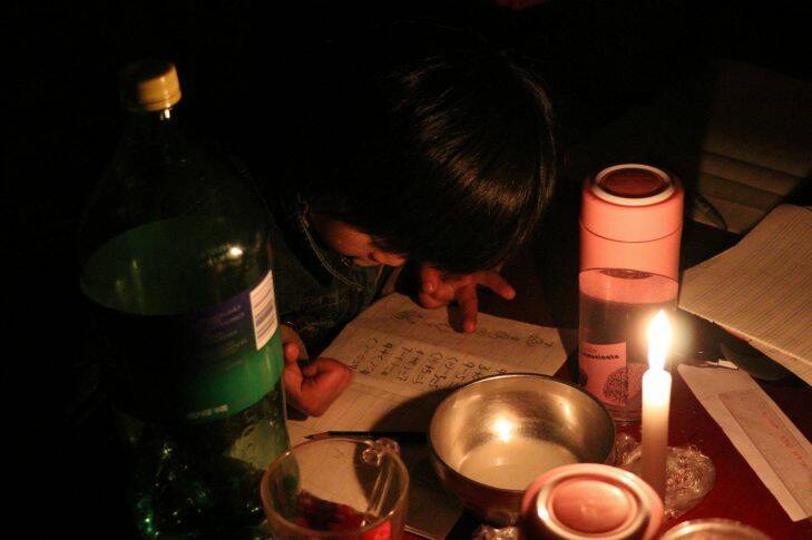 Xu Yuanyuan, 7, doing her math homework by accounting her fingers at grim candle light on November 27, 2017 at Picun Village in Beijing. .