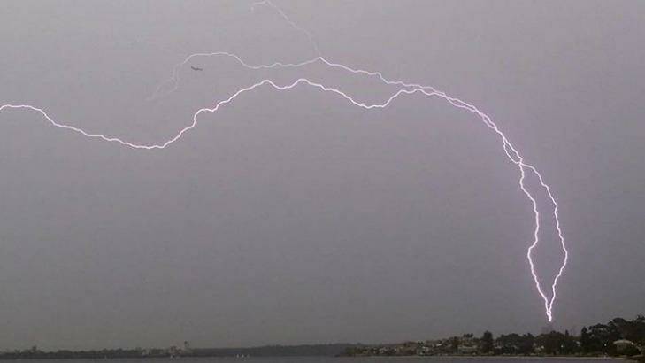 Lightning seems to threaten a plane and the BHP tower. Photo: www.lukebakerphoto.com
