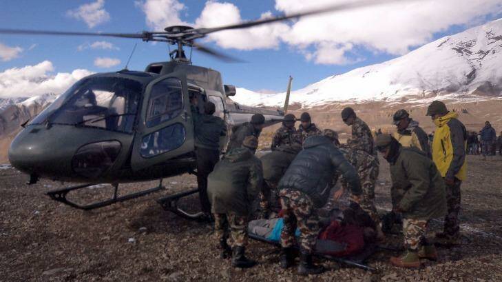 An injured survivor of a snow storm is assisted by army personel into a Nepalese Army helicopter. Photo: AFP/ Nepal Army