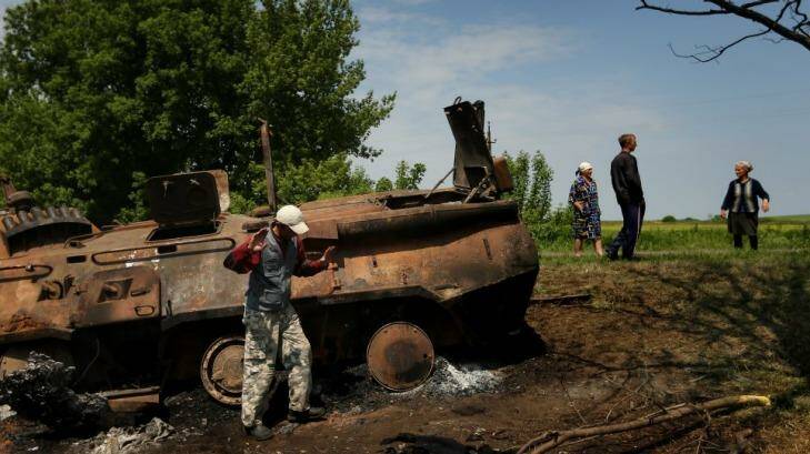 Locals stand near remains of a destroyed Ukrainian APC. Photo: Kate Geraghty