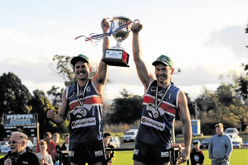 South Launceston captain Leigh Harding and coach Aaron Viney hold up last year's premiership cup.