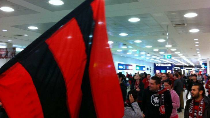 Wanderers fans cram into the arrivals area at Sydney Airport.