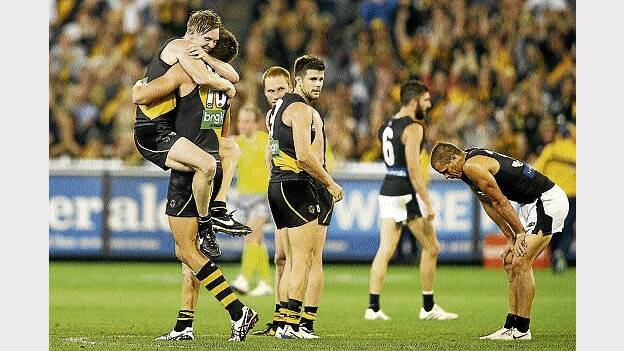 Richmond's Jack Riewoldt and teammate Shaun Hampson celebrate the Tigers' tight win against the Blues as Carlton's Ed Curnow slumps in disappointment after the final siren last ight. Picture: GETTY IMAGES.