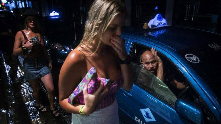 A taxi driver watches two schoolies walk past in Bali. Photo: Nic Walker