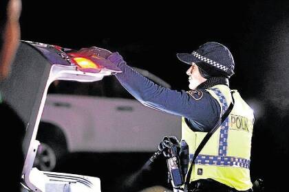 5-6-2015 pic Scott GelstonTasmanian Police Operation Northern Lockdown. A police officer searches a car at the checkpoint on the Midland Highway at Perth