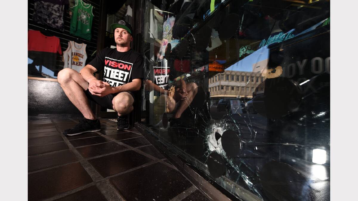 Wanted Street Wear owner Luke Dawson examines the damage caused after a hammer was thrown through the  window of his Launceston shop. Picture: MARK JESSER