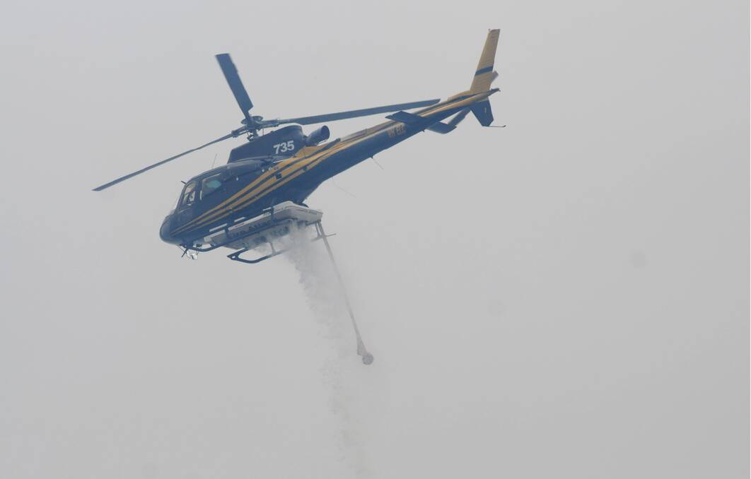 A chopper drops water over the fire at Lefroy on Wednesday afternoon. Picture: Geoff Robson