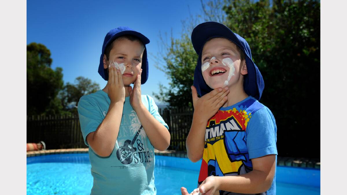 Launceston boys Lucas Chandler, 7, and Wesley Burgess, 7 , add a bit of slip, slop and slap before heading into the sunshine on Tuesday. Picture: GEOFF ROBSON