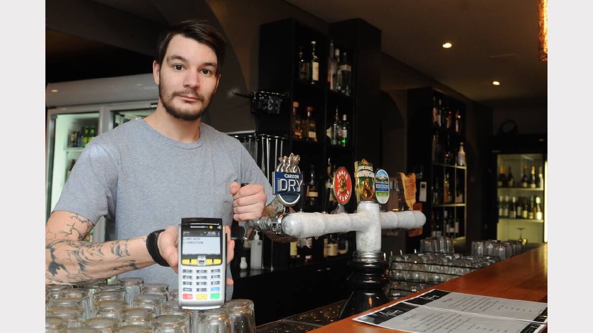Alchemy Bar and Restaurant duty manager Alex McNulty with an EFTPOS machine. Picture: Paul Scambler