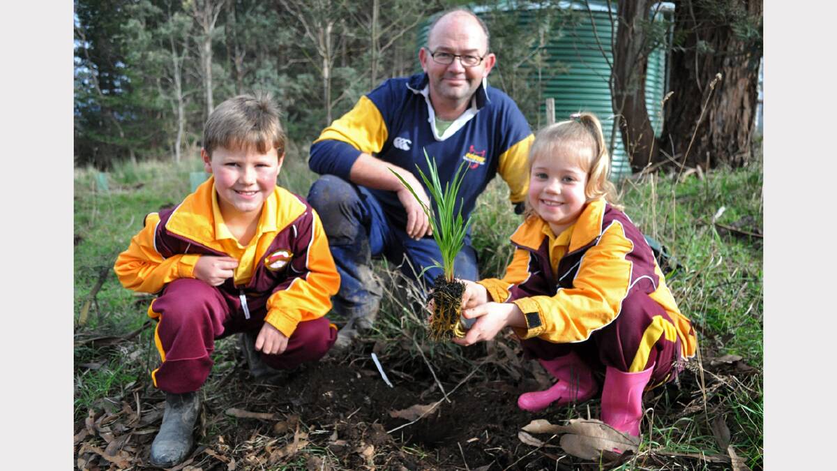 Bracknell Primary School grade 1 pupils Josh Spencer and Charlotte Boon plant a Tasmanian native grass with school volunteer garden co-ordinator Ian Mackenzie.