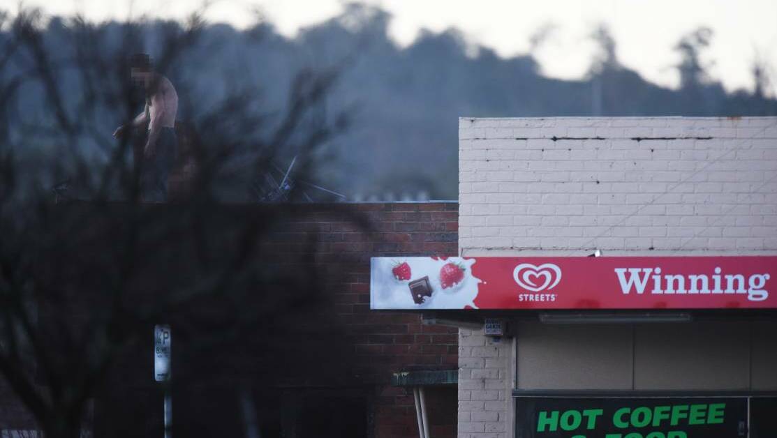 man on the roof of the property adjoing the Winning Post Takeaway speaks to police on the ground. Picture: Scott Gelston.