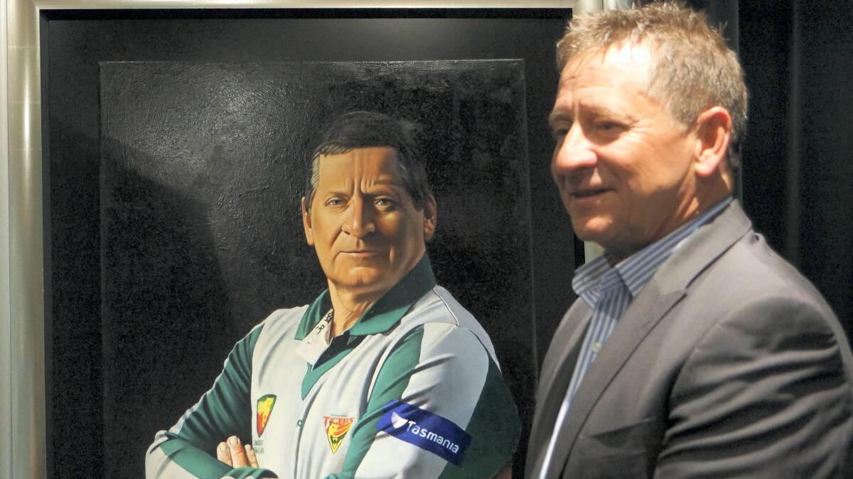 Former Tassie Tigers cricket coach Tim Coyle beside the portrait of himself which was unveiled  at  Blundstone Arena  on Friday.
