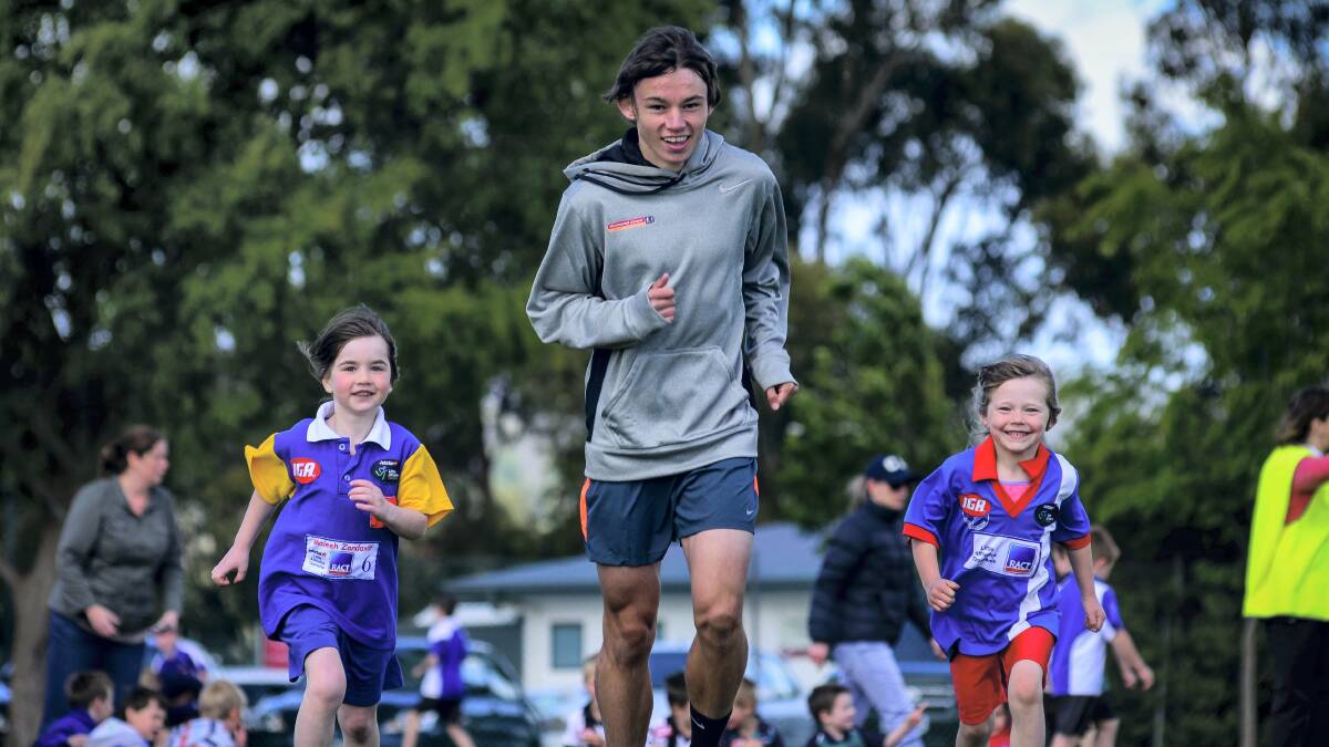 Jack Hale, of Hobart, takes a jog with   under-6 little athletes Maleeh Zandervar  and   Georgie Natoli  
