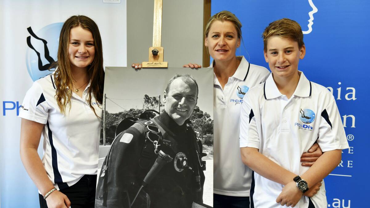 Charlea, 15, Tach and Beau Malkin, 12, with a photo of Phil Malkin in dive gear.

Picture: SCOTT GELSTON