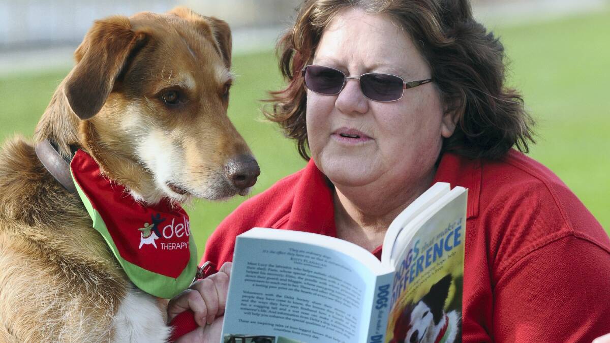 Delta Therapy Dog Sammy  and his owner Joanne Cox, of Ulverstone, reading the Delta Society's newest book, Dogs That Make a Difference.  Picture: PAUL SCAMBLER