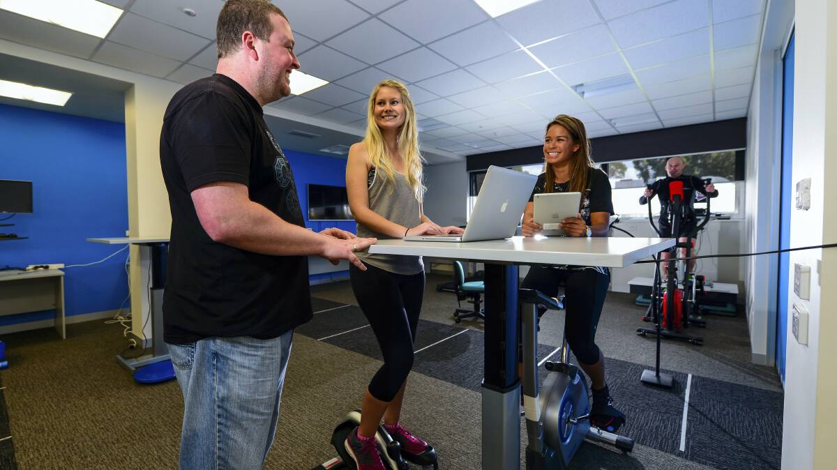 UTAS active work laboratory director Scott Pedersen, psychology student Bridget Russell, health and physical education student Malia Valenciano and health and physical education lecturer Casey Mainsbridge discuss desk options in workplaces. Picture: PHILLIP BIGGS