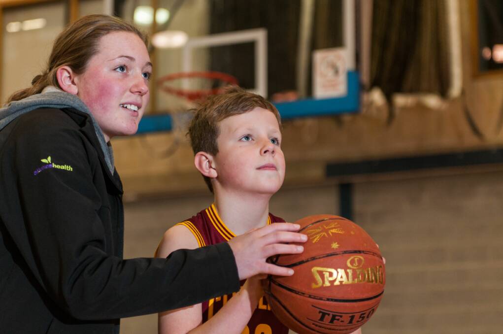 Looking up: Tornadoes basketball player Sophie Ackerly helps Tyler Alexander line up a shot at the clinic at Elphin Sports Centre. Pictures: Phillip Biggs