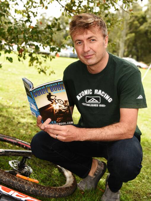 Ride on time: Author Travis Deane with his Tasmanian Mountain Bike Guide Book. Picture: Scott Gelston