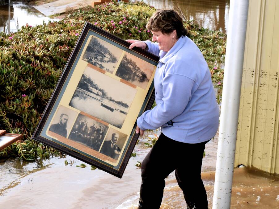 Framed: Kim Wilson removes rare photos from the flooded Tamar clubhouse.