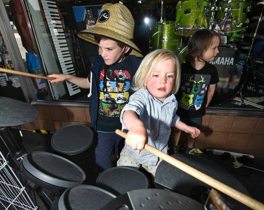 TUNES: Zac, 7, and Banjo Crowden, 2, play the electric drums at Barratts music while their brother Ronnie watches on. 